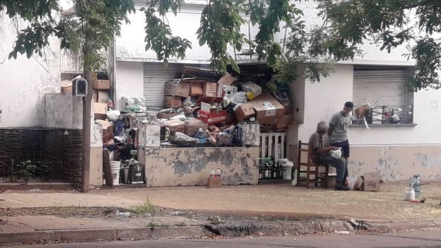 vecinos preocupados por un hombre que acumula cajas, botellas y basura en la puerta de su casa
