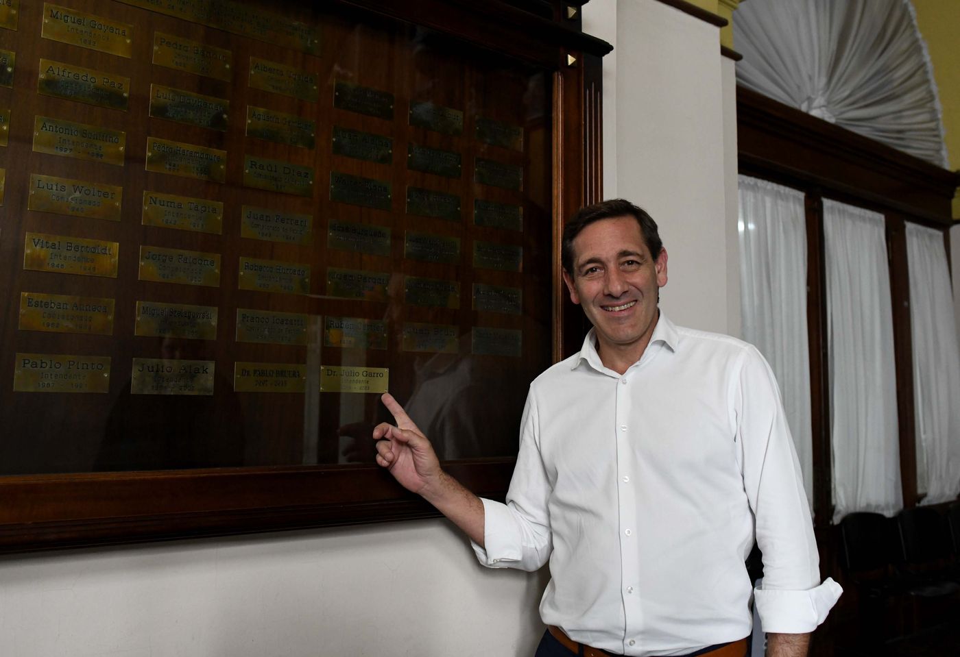 Julio Garro en el hall de entrada de la Municipalidad, junto a las placas de todos los intendentes de la historia