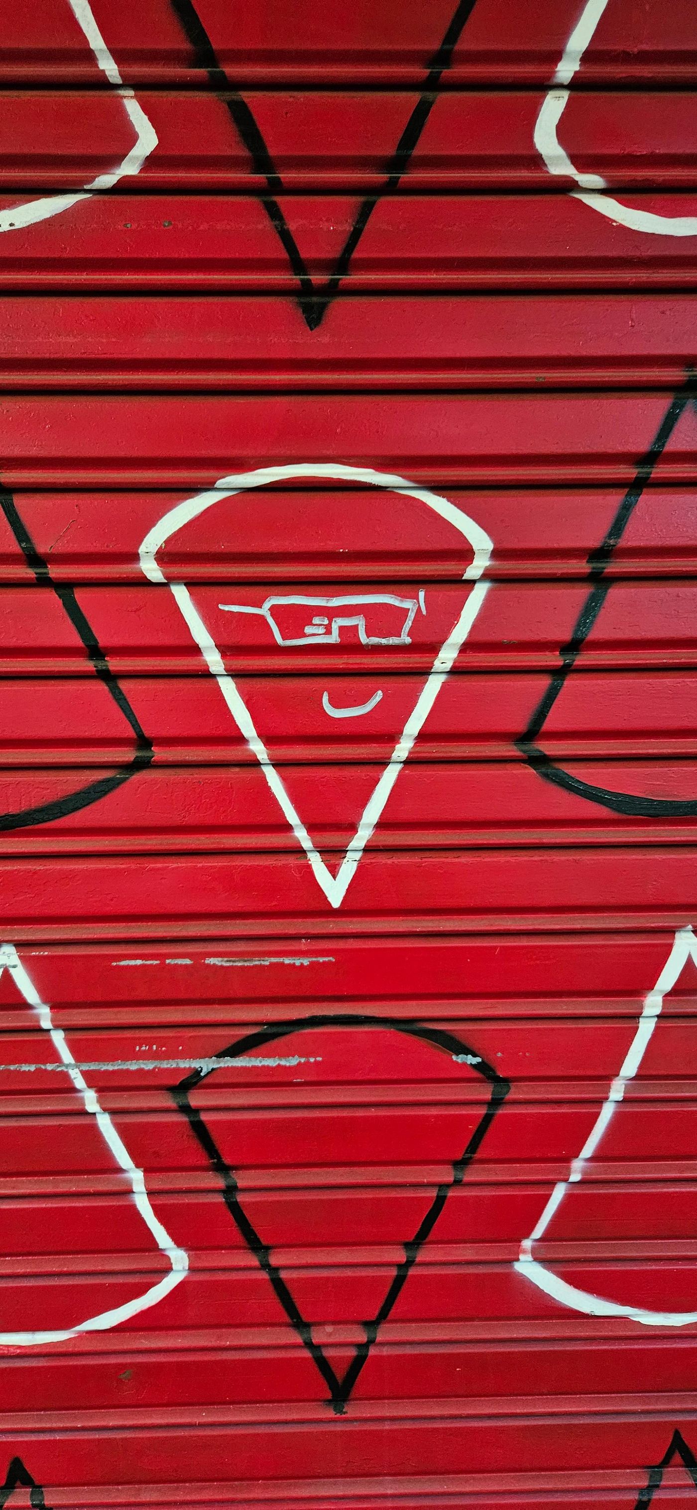 Las porciones de pizza dibujada en la cortina metálica y la primera carita aportada por el graffitero anónimo Las porciones de pizza dibujada en la cortina metálica y la primera carita aportada por el graffitero anónimo
